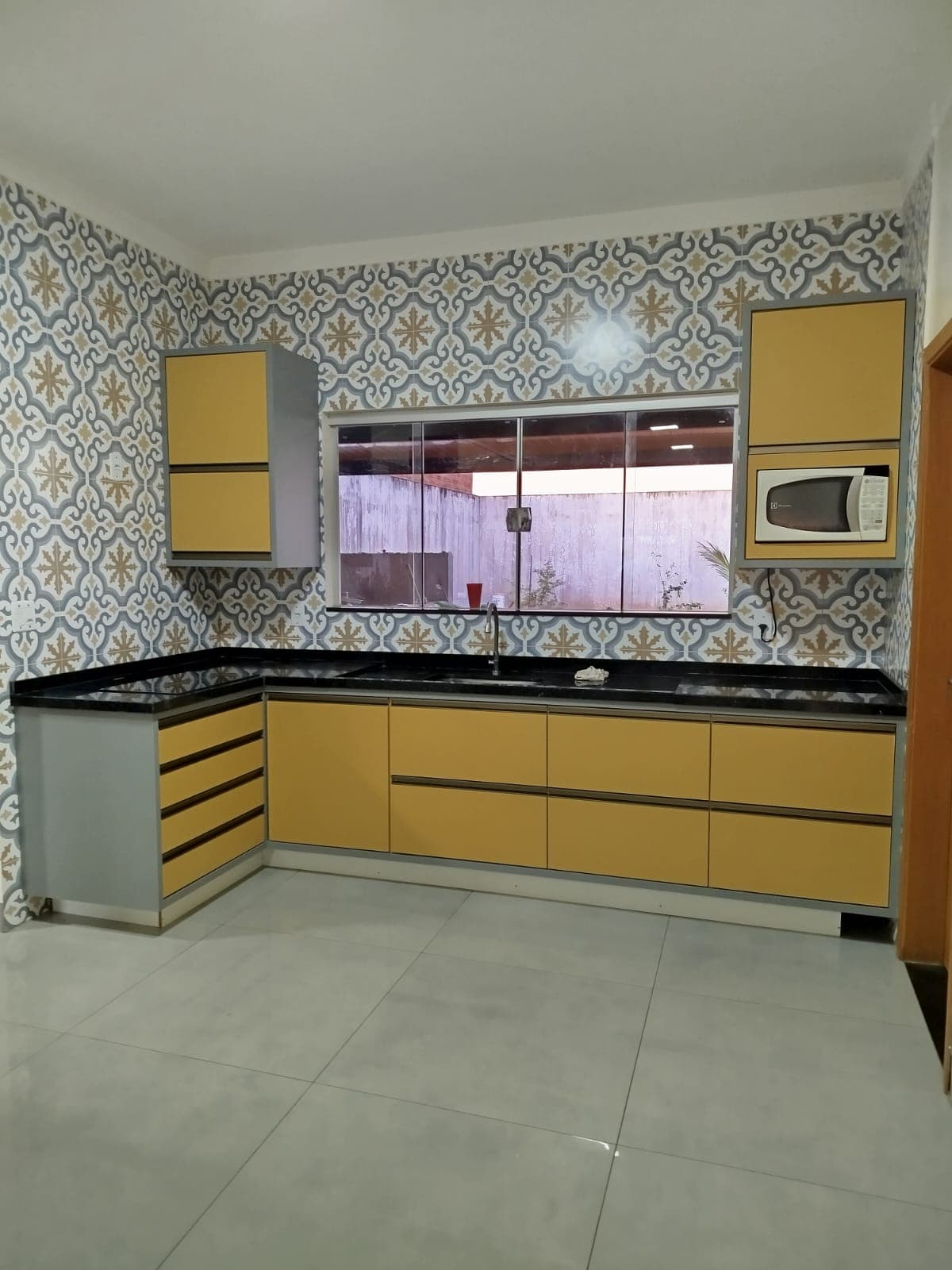 Cozinha planejada em amarelo com azulejo hidráulico
