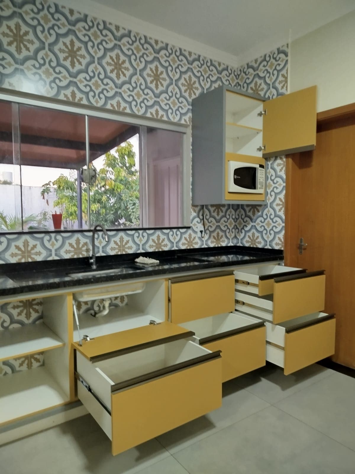 Detalhe de armário amarelo com micro-ondas embutido