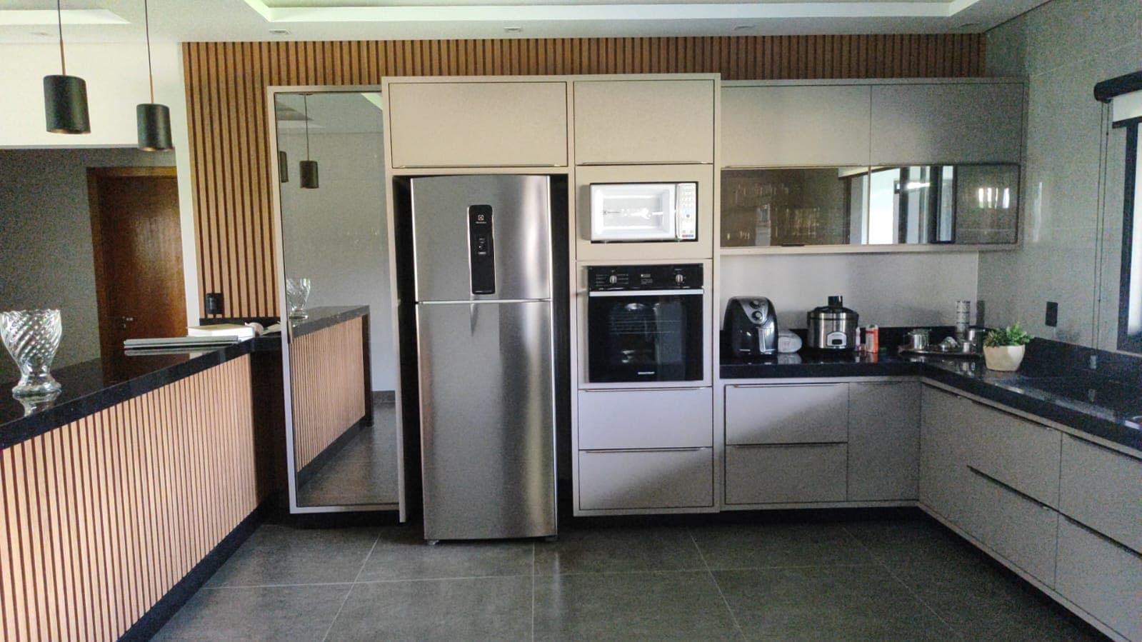 Cozinha cinza com painel ripado e coluna de geladeira integrada