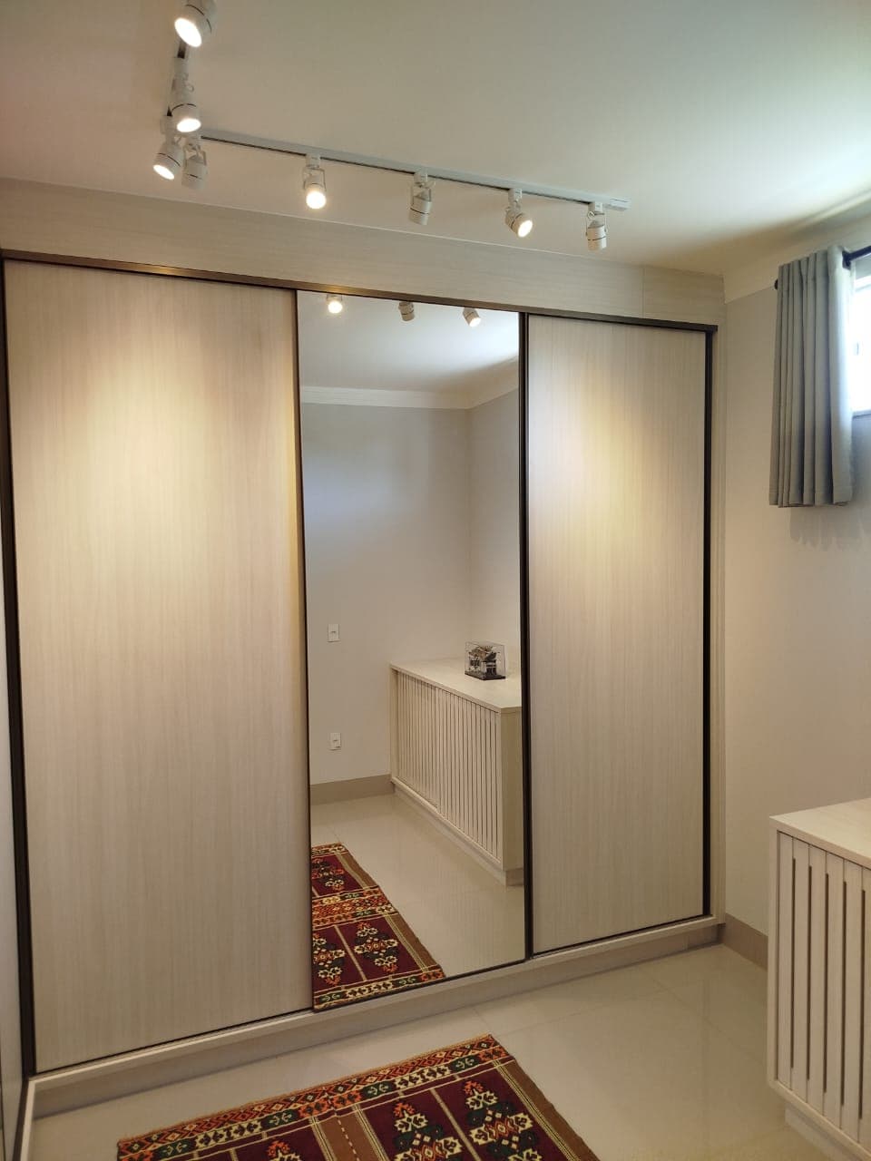 Guarda-roupa espelhado em tom bege com tapete kilim