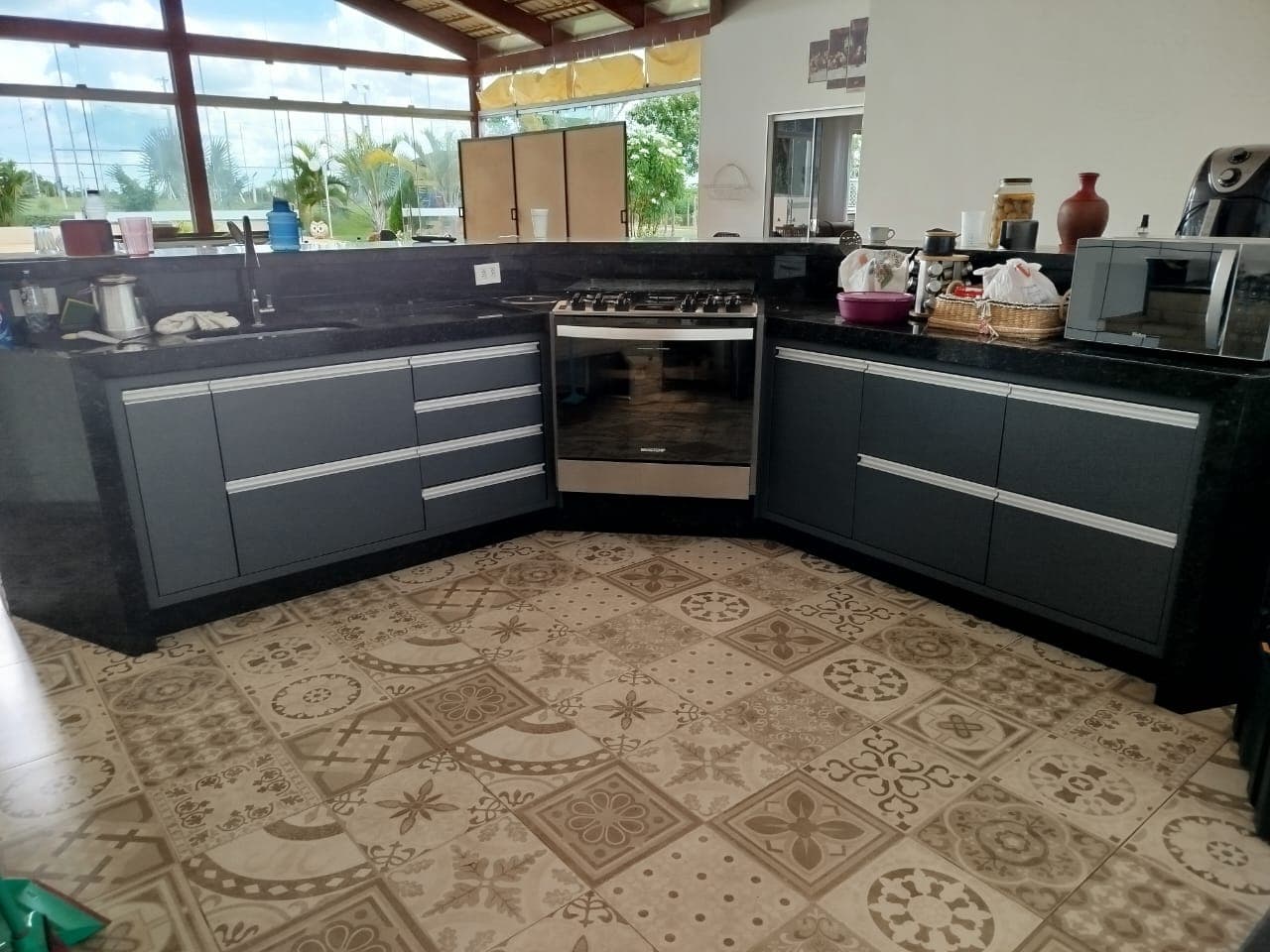 Área gourmet coberta com bancada preta e vista para a piscina